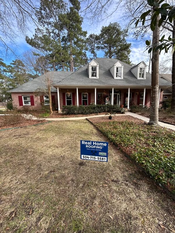 House with roofing company sign in yard.