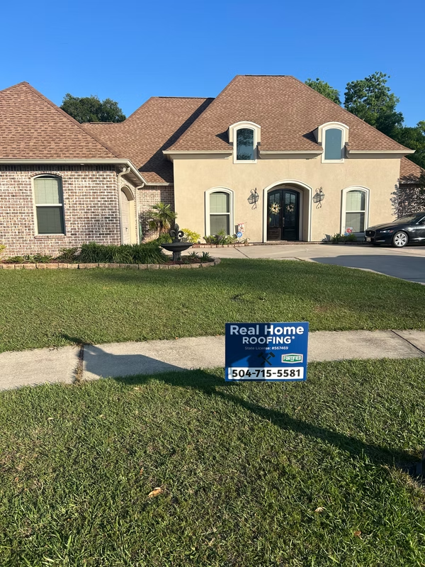 House with roofing company sign in yard.
