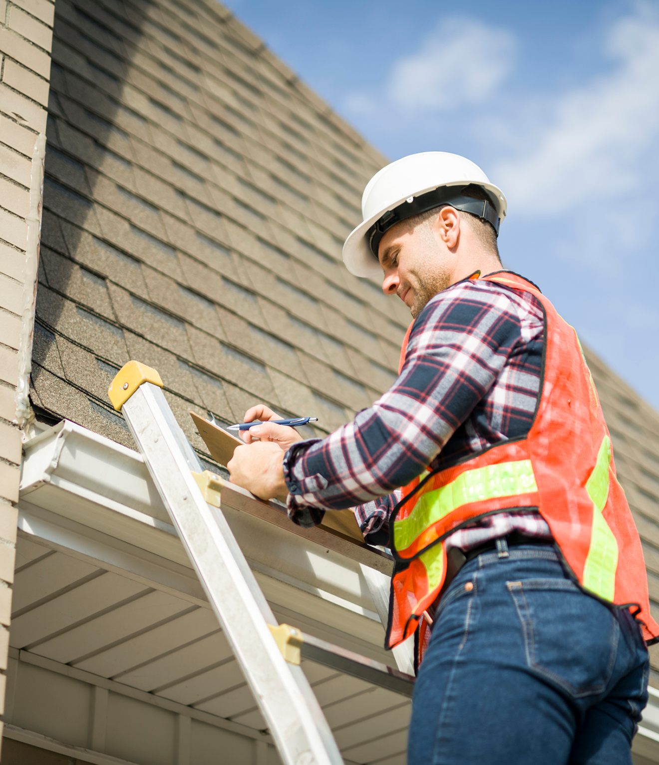 Inspector on ladder examining roof shingles.