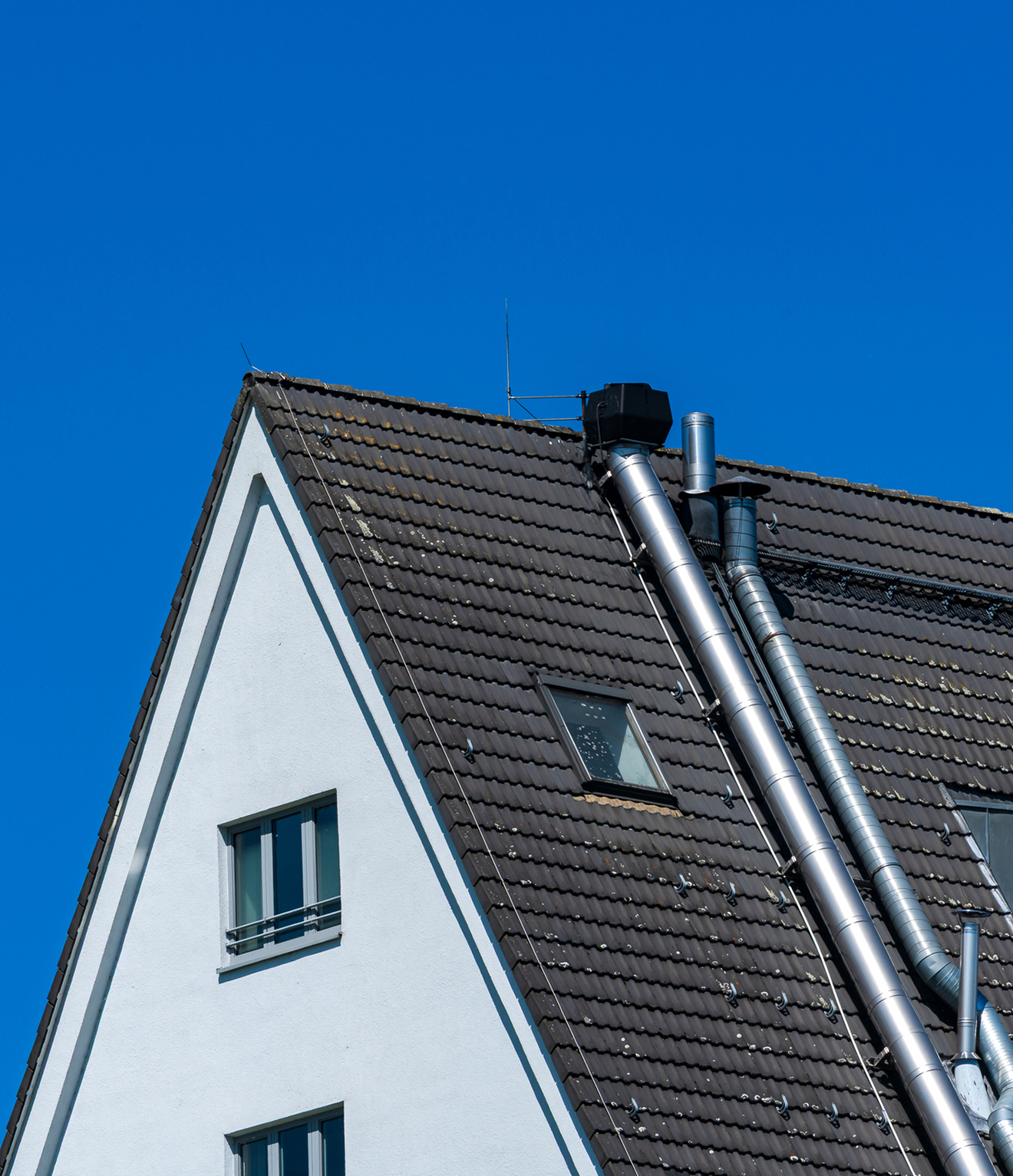 A-frame roof with chimney against blue sky.