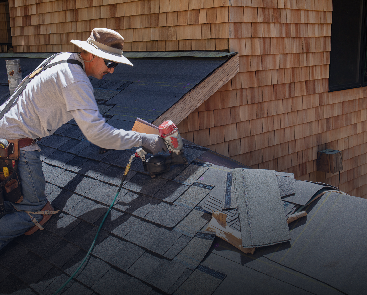 Roofer installing shingles on a house.