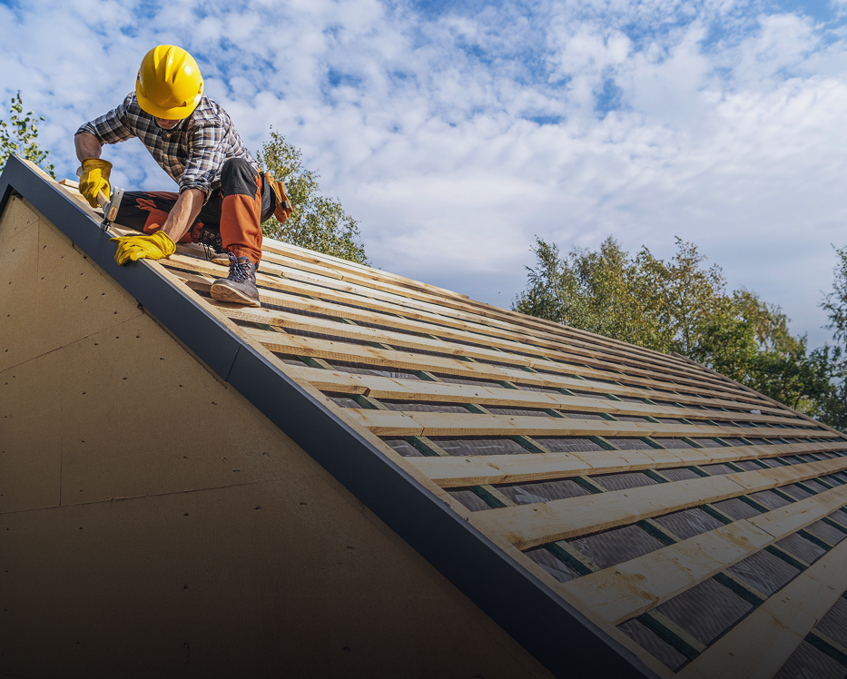 Worker installing roofing on a wooden structure.