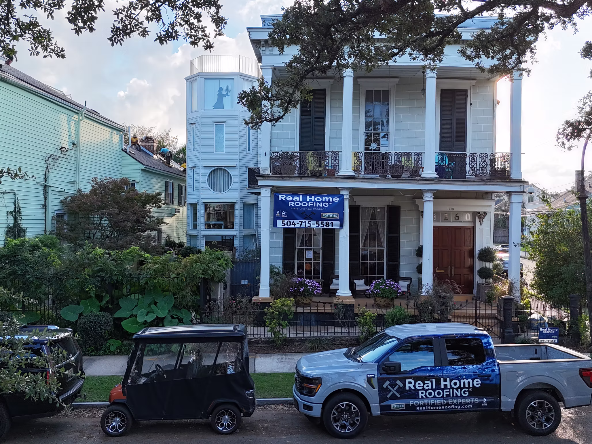 White house with Real Home Roofing sign.