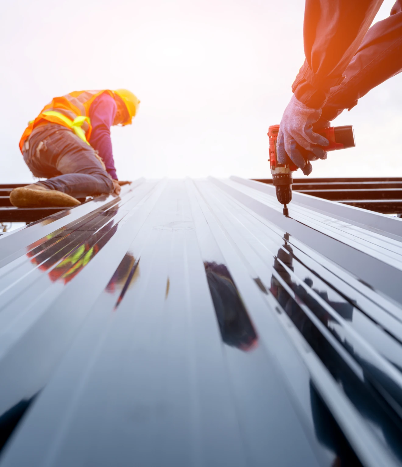 Construction workers installing metal roof panels.
